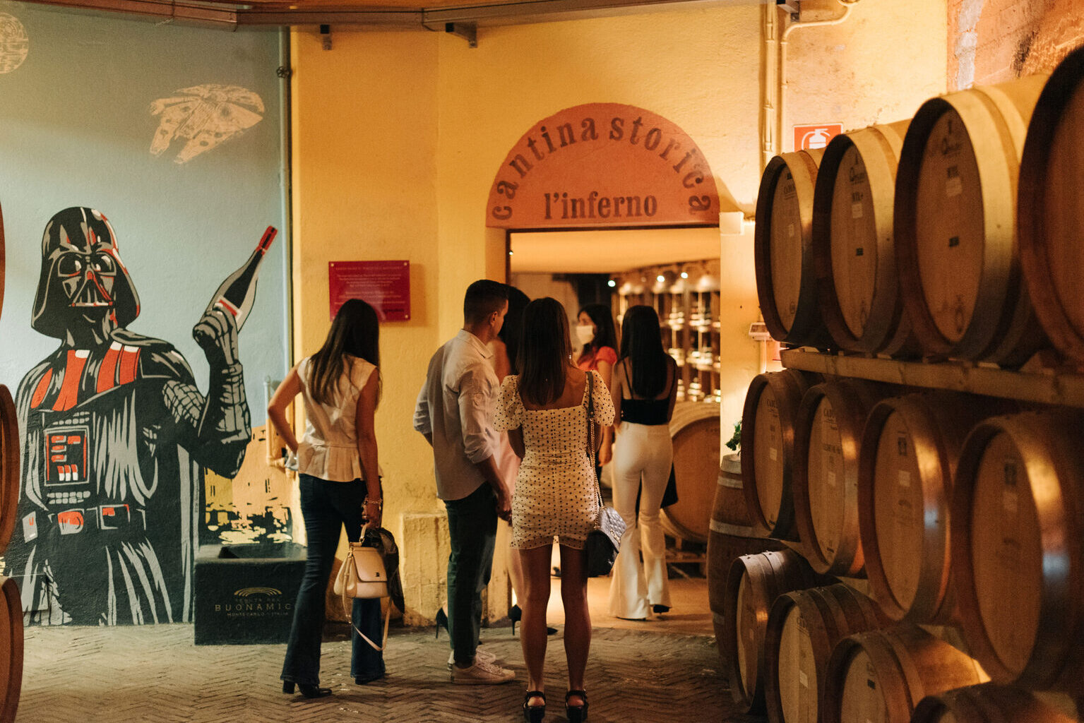Visitors entering the historic Cantina Storica l'Inferno at Buonamico winery in Montecarlo with oak barrels, Tuscany Italy