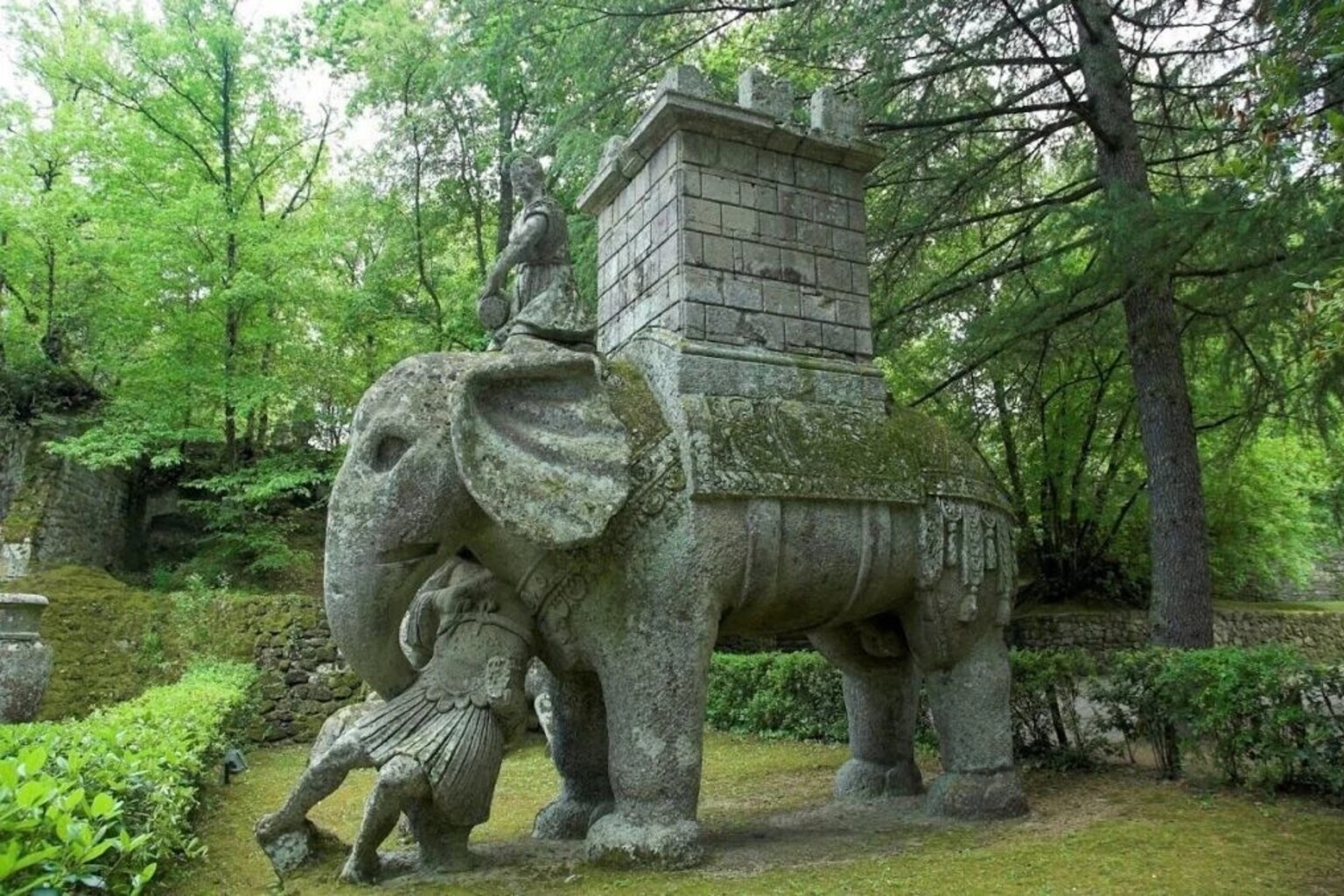 Giant stone elephant sculpture carrying a tower with a soldier figure at its feet, Sacro Bosco di Bomarzo monster garden, Lazio Italy