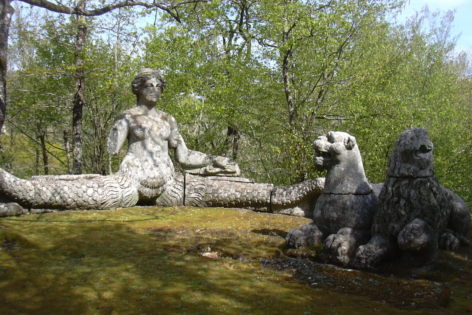 Stone siren and sphinx sculptures covered in moss in the Sacro Bosco di Bomarzo mannerist garden, Lazio Italy