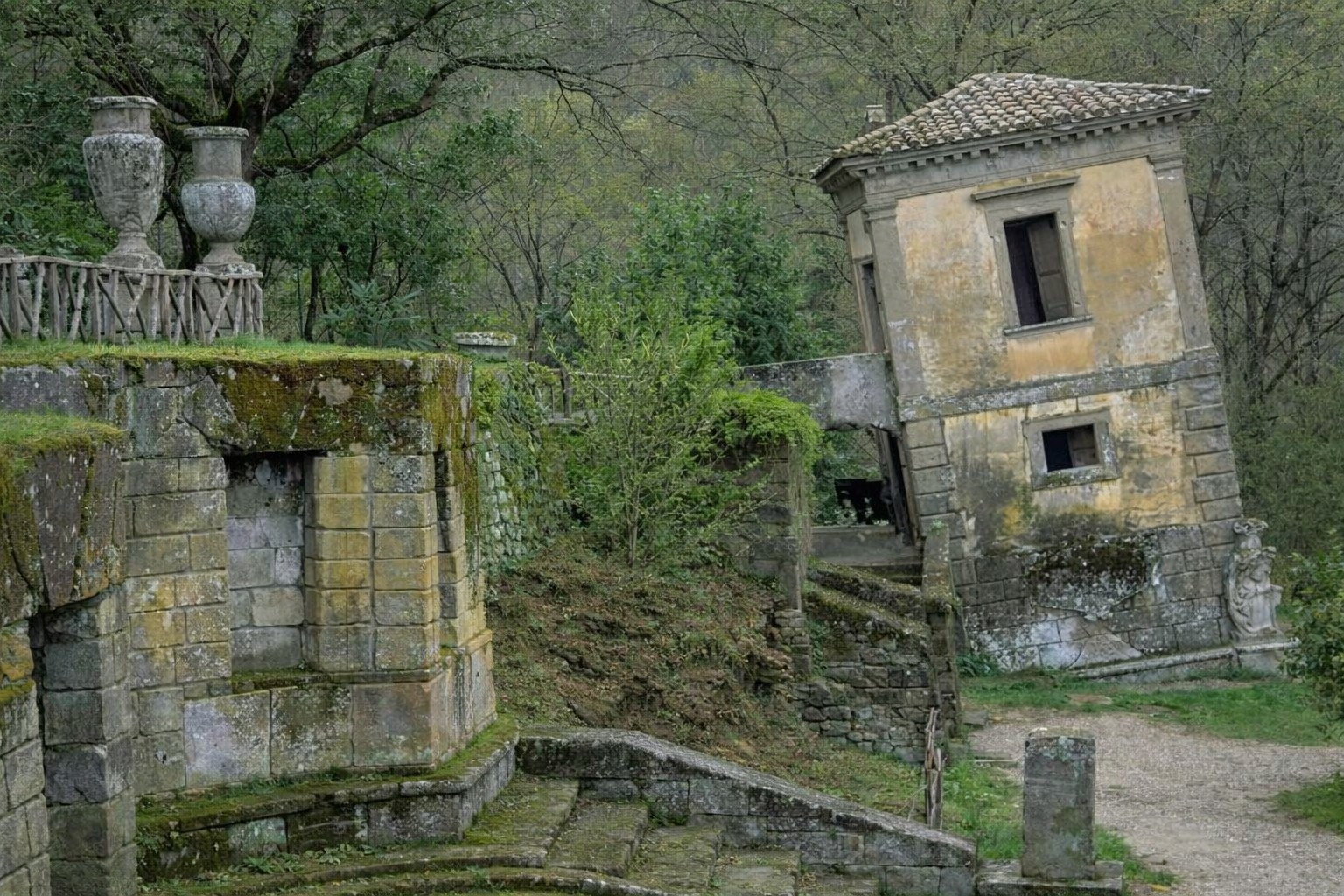 The deliberately tilted house among moss-covered stone structures at the Sacro Bosco di Bomarzo, Lazio Italy