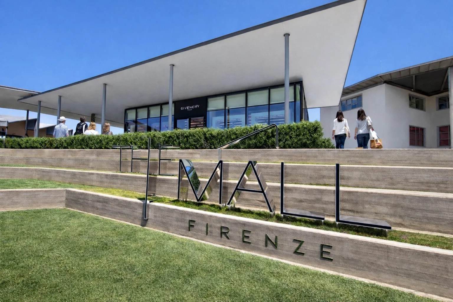 The Mall Firenze luxury outlet entrance with modern architecture and visitors, Leccio Reggello Tuscany Italy