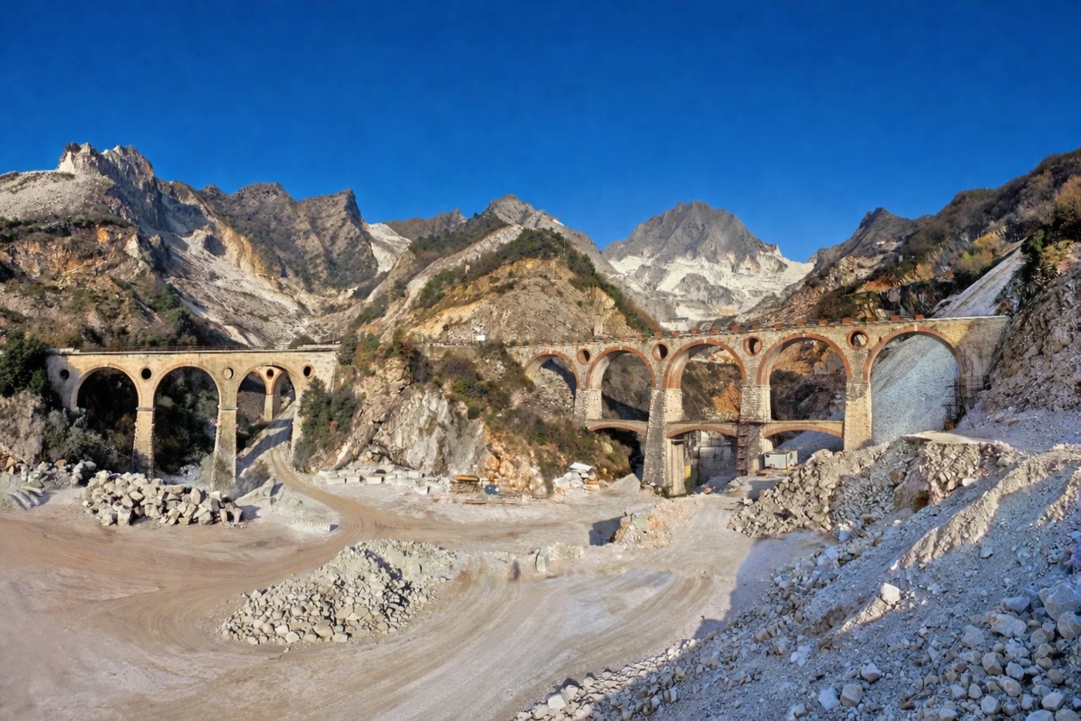 Carrara marble quarries with Roman stone arches and white marble mountains