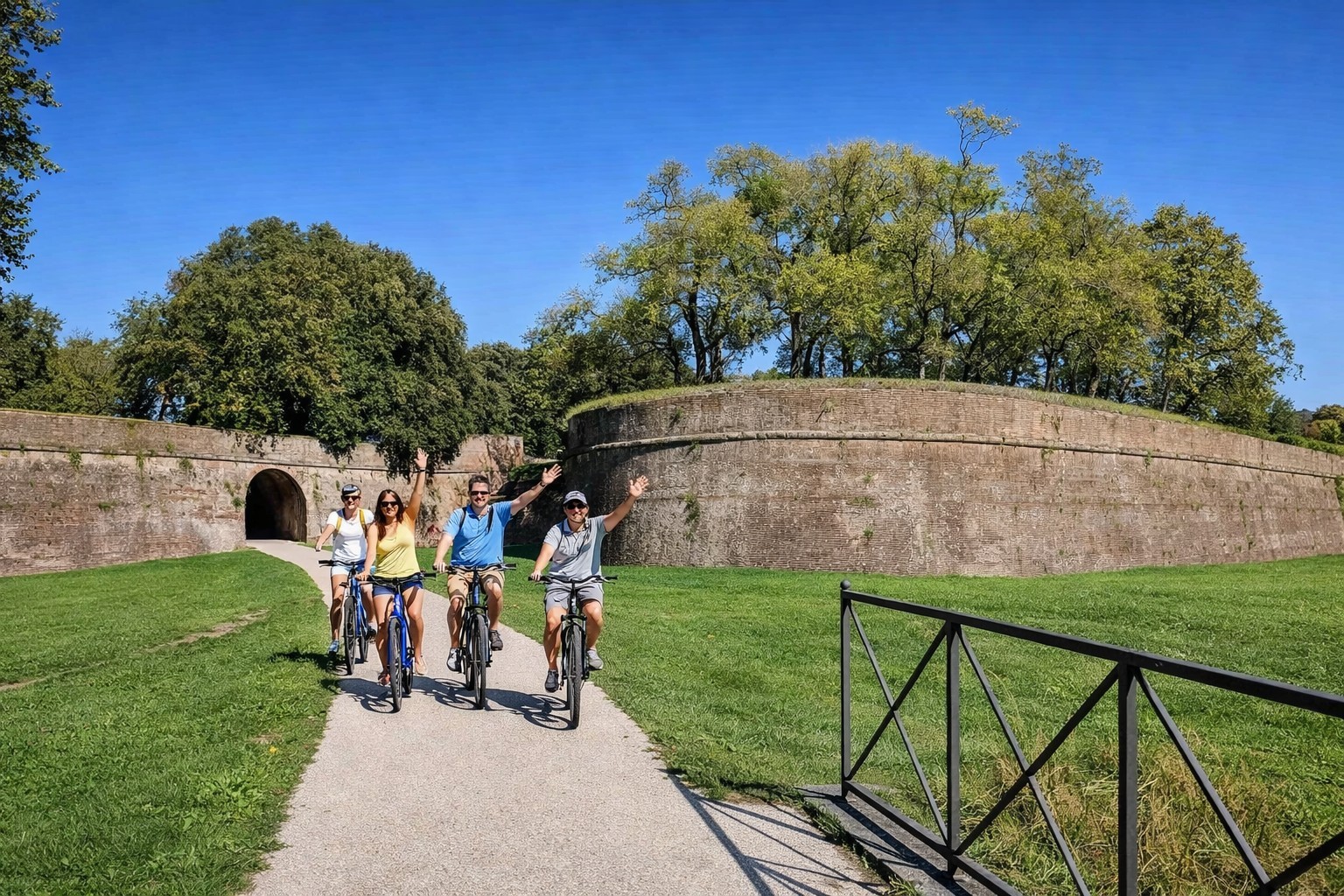 Group of friends cycling on top of the Renaissance walls of Lucca — the most perfectly preserved city walls in Italy, Tuscany