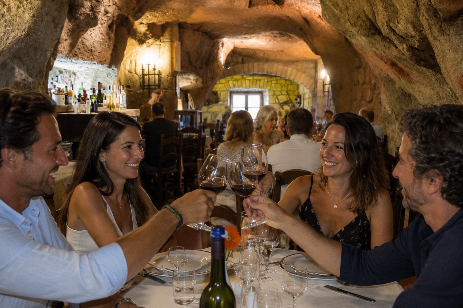 Friends toasting red wine inside Le Grotte del Funaro cave restaurant carved into the tufa rock in Orvieto, Umbria Italy