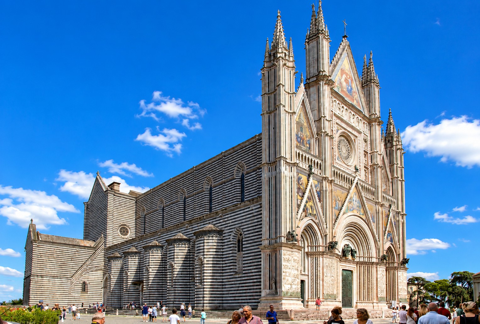 Orvieto Cathedral Gothic facade with striped marble walls and golden mosaics under blue sky — private transfer Umbria