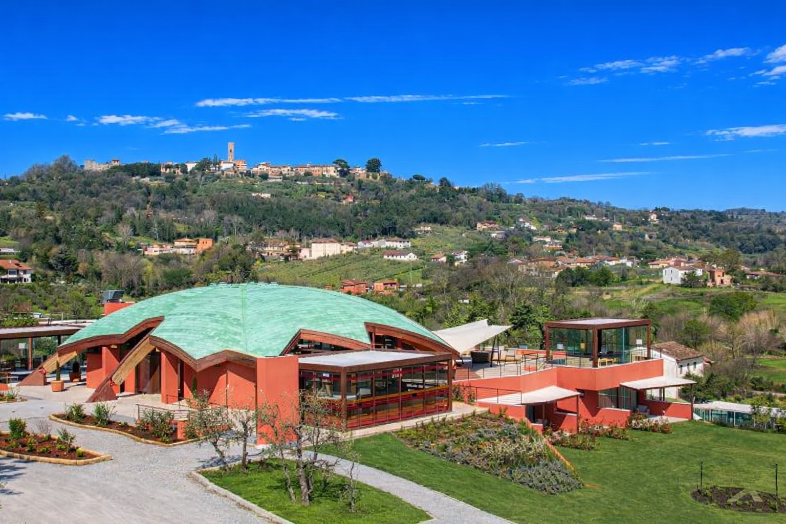 Aerial view of Fattoria del Buonamico winery in Montecarlo — modern cellar building with copper dome in the Tuscan hills