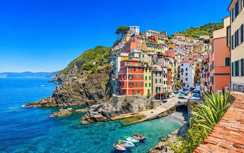 Riomaggiore harbour with colourful houses stacked on the cliffs above the turquoise sea, Cinque Terre Liguria Italy